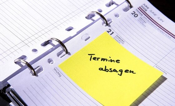 gelber postit mit der aufschrift termin absagen